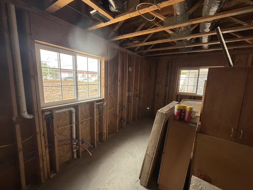 Interior room under construction showing exposed wall framing and ceiling joists